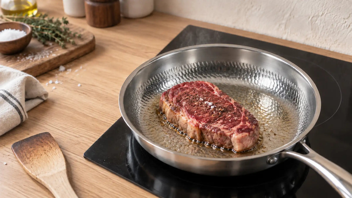 Steak qui saisit dans une poêle en titane martelé posée sur une plaque à induction