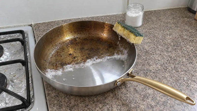 Nettoyer une poêle en inox au bicarbonate : la moitié frottée à l'éponge brille à nouveau, l'autre garde ses traces de cuisson