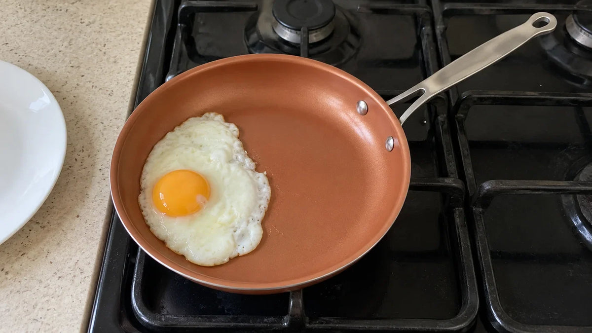 Utiliser une poêle en céramique : un œuf au plat qui glisse tout seul vers l'assiette, la poêle posée sur le gaz