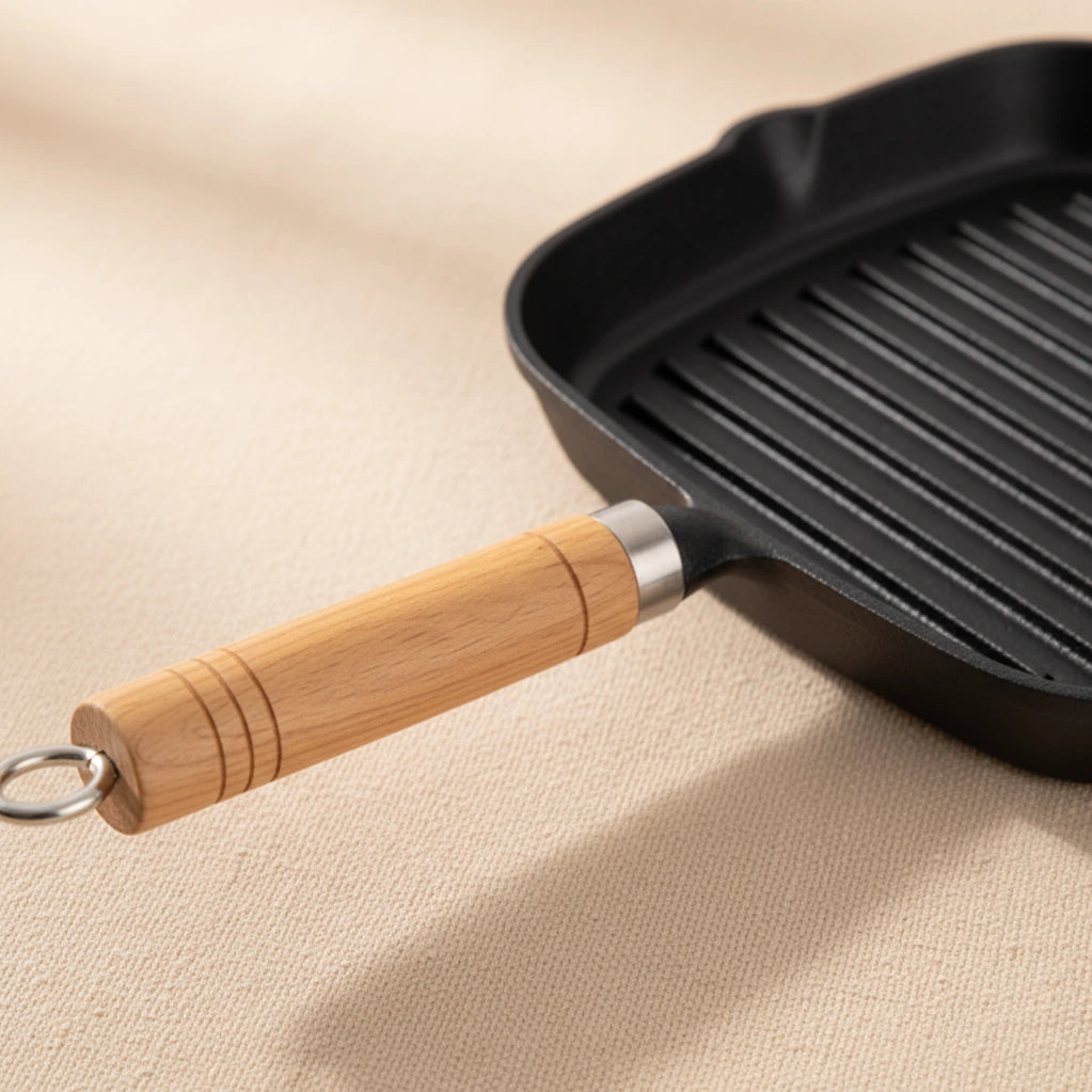 Poêle à Griller en Fonte 22 cm : détail du manche en bois sur fond beige.