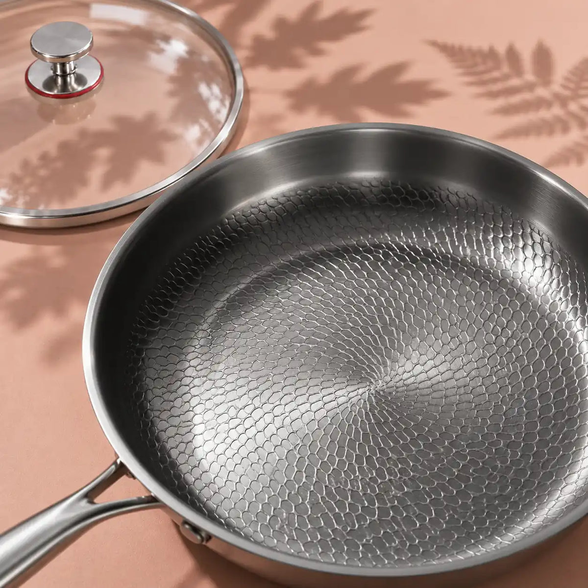 Surface de cuisson texturée de la poêle en titane 30 cm avec couvercle vue de dessus, le couvercle en verre posé à côté