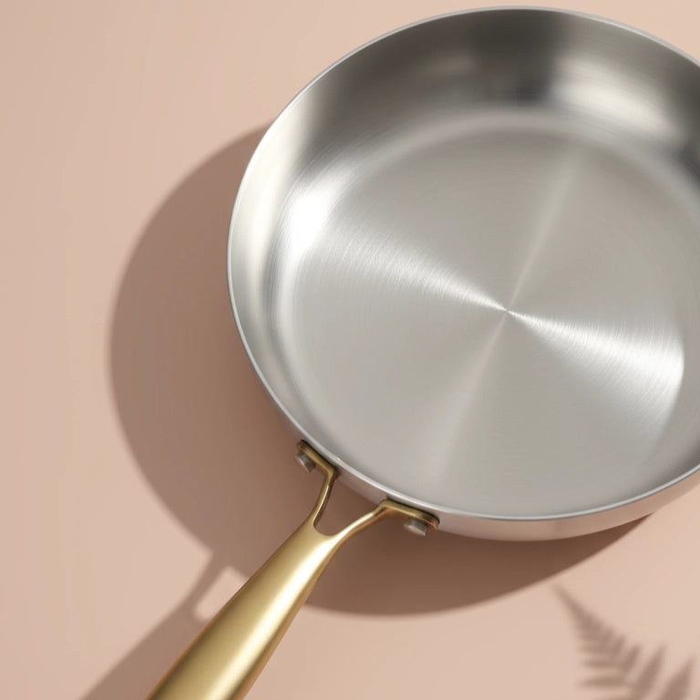 Surface de cuisson brossée de la poêle induction 22 cm vue de près, son manche doré au premier plan
