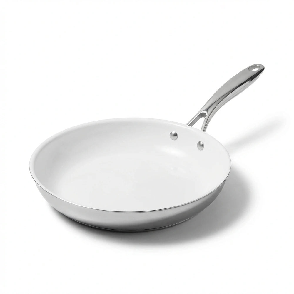 Vue en studio de la poêle inox céramique blanche isolée, prête pour l'exploration de ses caractéristiques techniques. Mise en évidence du manche en acier inoxydable brossé et du revêtement intérieur en céramique naturelle.