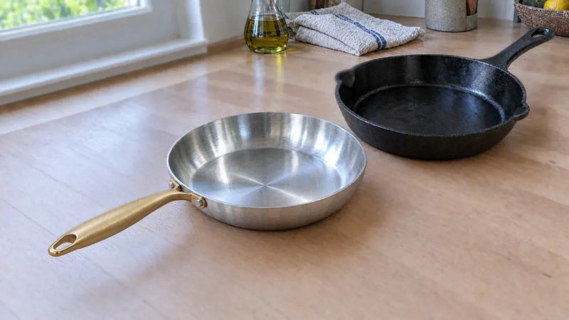 Faut-il culotter une poêle en inox ? Poêle en inox à manche doré posée à côté d'une poêle en fonte noire culottée