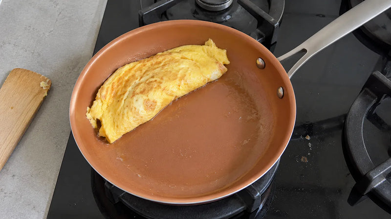Poêle en céramique et santé : une omelette pliée se détache toute seule sur le gaz éteint, à côté d'une spatule en bois