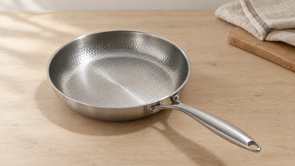 Poêle en titane martelé de 24 cm posée sur un plan de travail clair, sa surface de cuisson martelée gris argenté bien visible