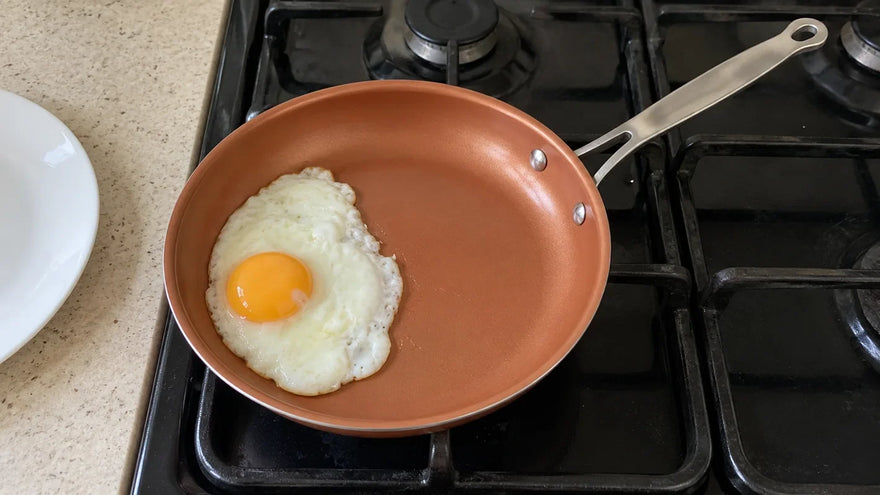 Utiliser une poêle en céramique : un œuf au plat qui glisse tout seul vers l'assiette, la poêle posée sur le gaz
