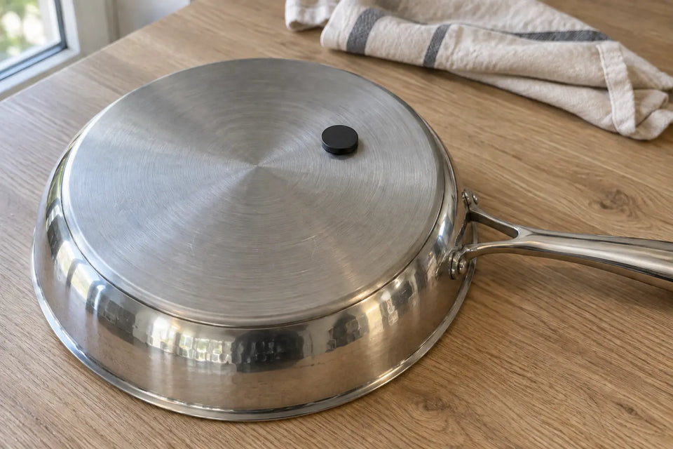 Petit aimant collé sous une poêle en titane retournée, sur sa face extérieure en inox brossé