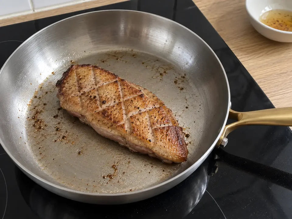 Magret de canard à la peau quadrillée et dorée, cuit dans sa propre graisse dans une poêle en inox