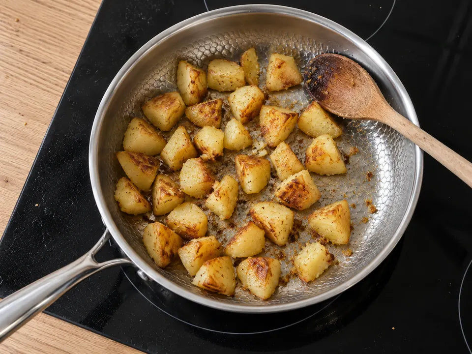 Pommes de terre sautées dans une poêle en titane : les morceaux posés près du bord sont aussi dorés que ceux du centre