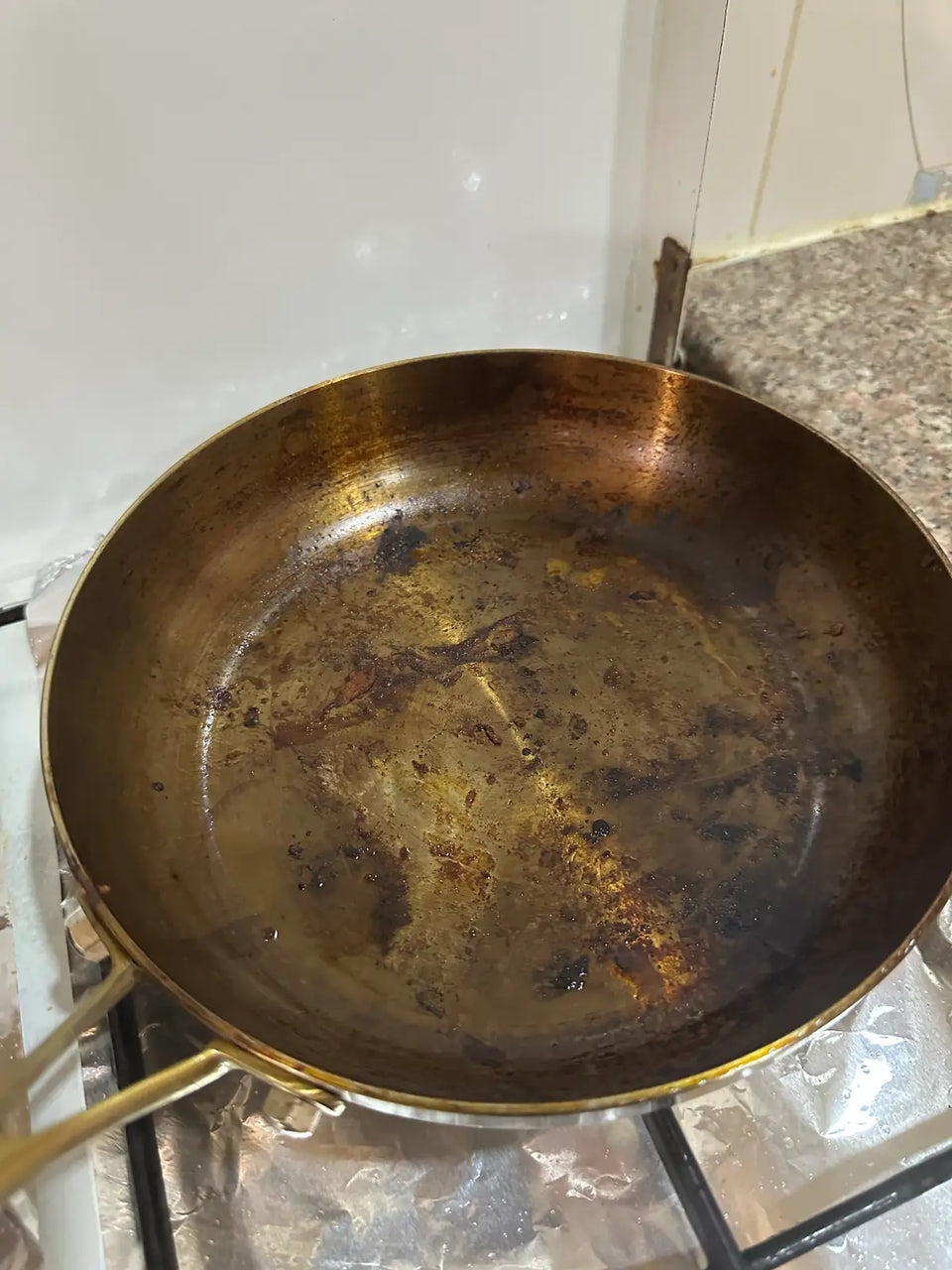 Poêle en inox brûlée après une saisie à feu vif : surface de cuisson brunie et résidus carbonisés, avant nettoyage