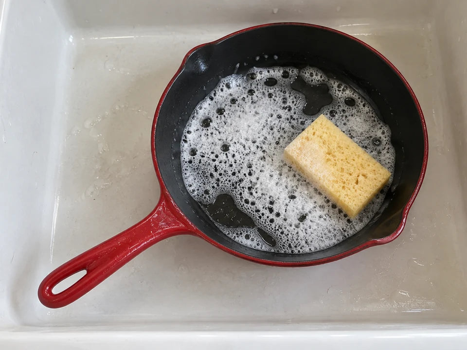 Nettoyer une poêle en fonte émaillée : poêle rouge à l'intérieur noir lavée avec une éponge douce et un peu de mousse