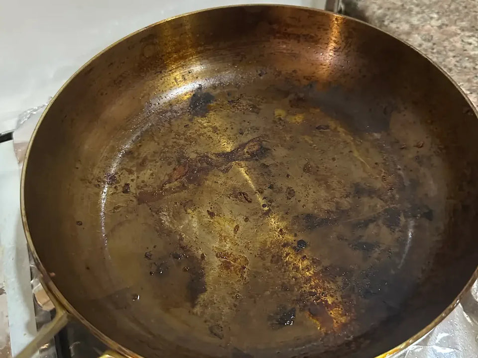 Taches sur une poêle en inox à nettoyer : voile brun d'huile cuite et petites traces noires de brûlé