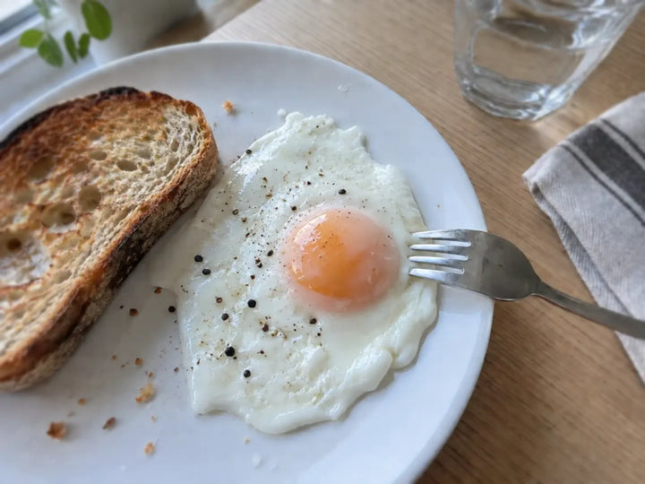Œuf au plat au jaune voilé de blanc, cuit une minute sous un couvercle, servi avec une tartine