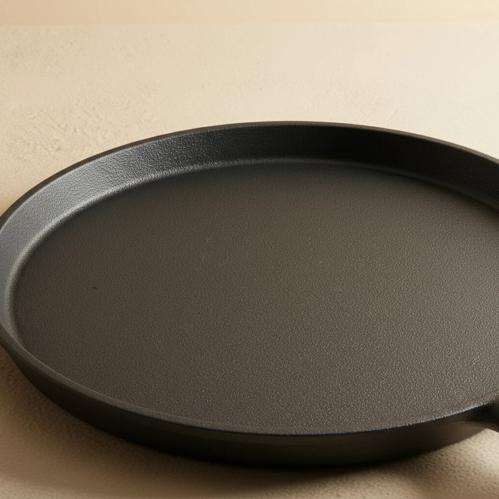 Gros plan sur la surface de cuisson noire de la poêle à crêpe en fonte 20 cm, montrant la texture du matériau.