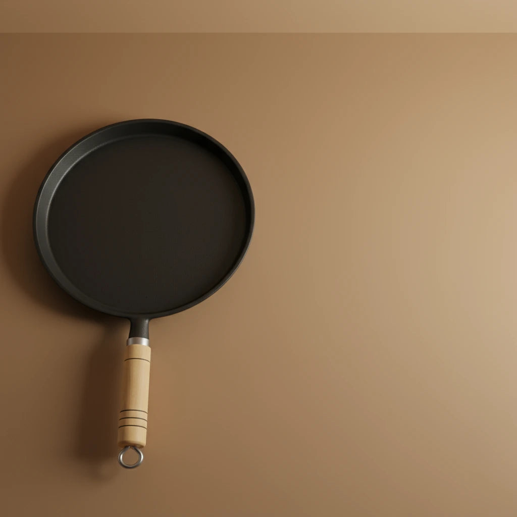 Poêle à crêpe en fonte 20 cm avec manche en bois, vue de dessus partielle sur un fond marron uni.