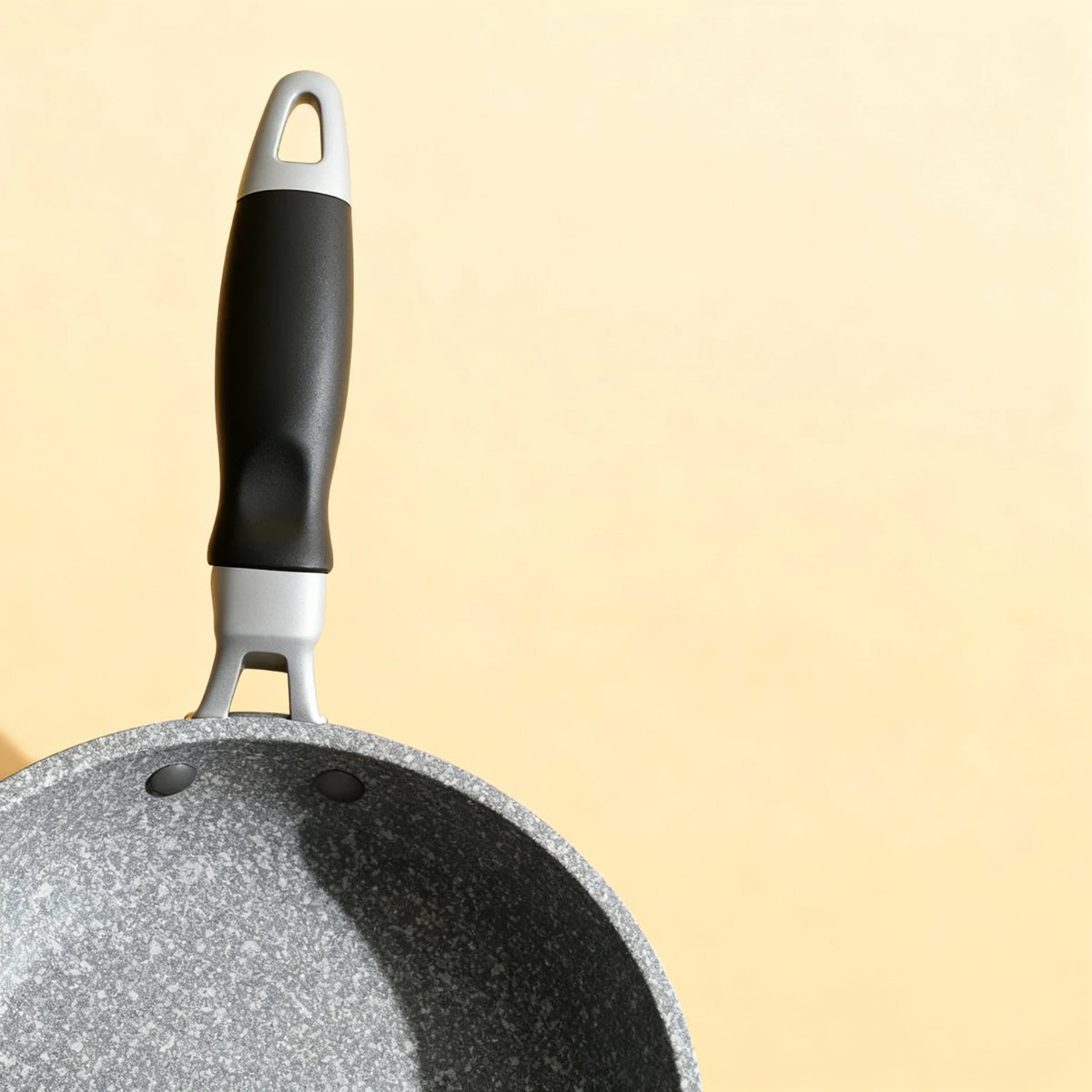 Gros plan sur la poignée ergonomique noire et grise de la poêle en aluminium 20 cm. Prise en main confortable et antidérapante.