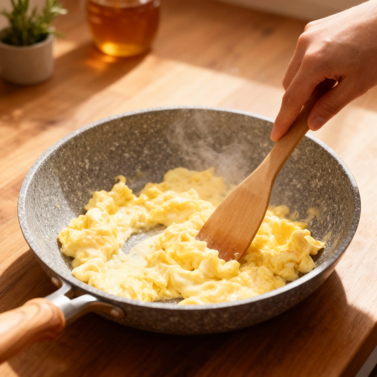 Poêle en aluminium induction 26 cm : préparation d’œufs brouillés avec une spatule en bois.