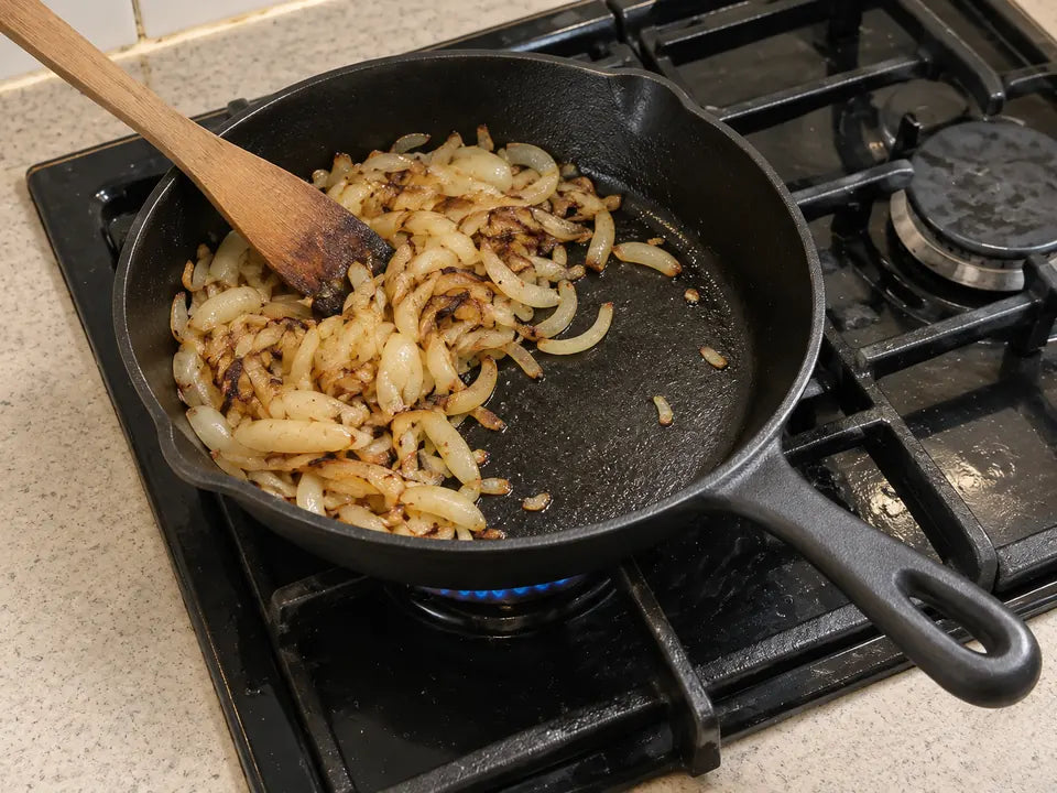 Premières cuissons dans une poêle en fonte culottée : des oignons revenus avec un peu de matière grasse renforcent la patine