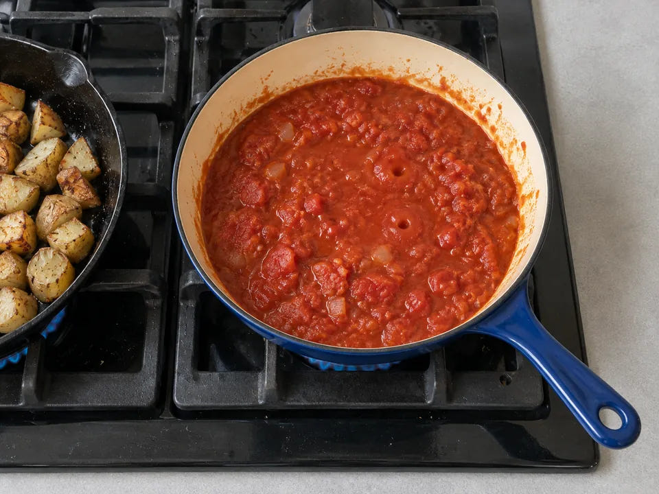 Poêle en fonte émaillée : une sauce tomate mijote dans une poêle émaillée bleue, à côté d'une poêle en fonte naturelle
