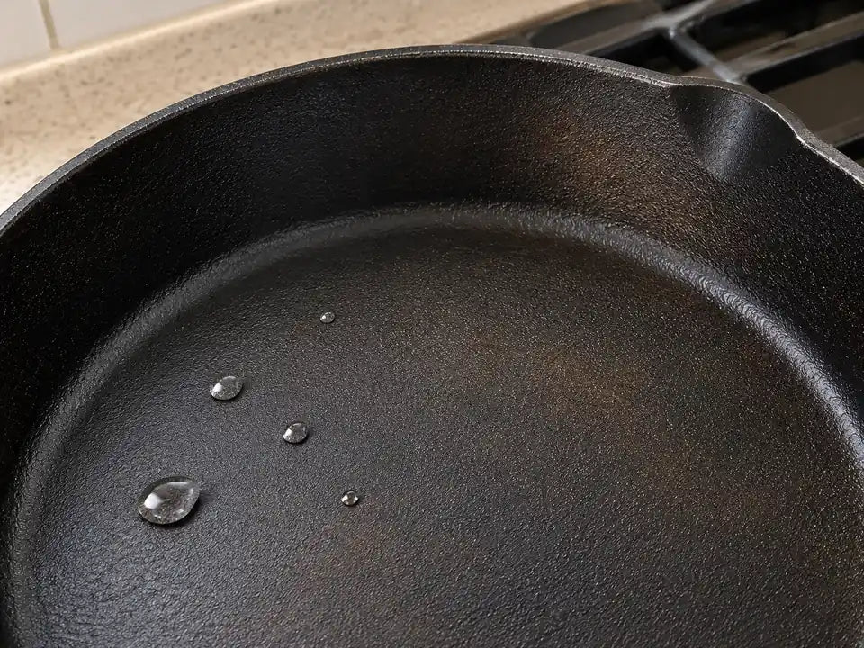 Préchauffer une poêle en fonte pour qu'elle ne colle pas : des gouttes d'eau roulent en petites billes dans la poêle