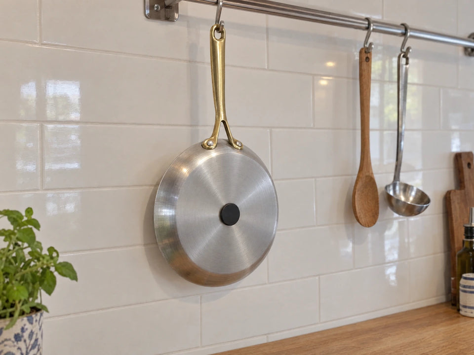 Aimant qui tient sous une poêle en inox suspendue, preuve que sa couche extérieure fonctionne sur l'induction