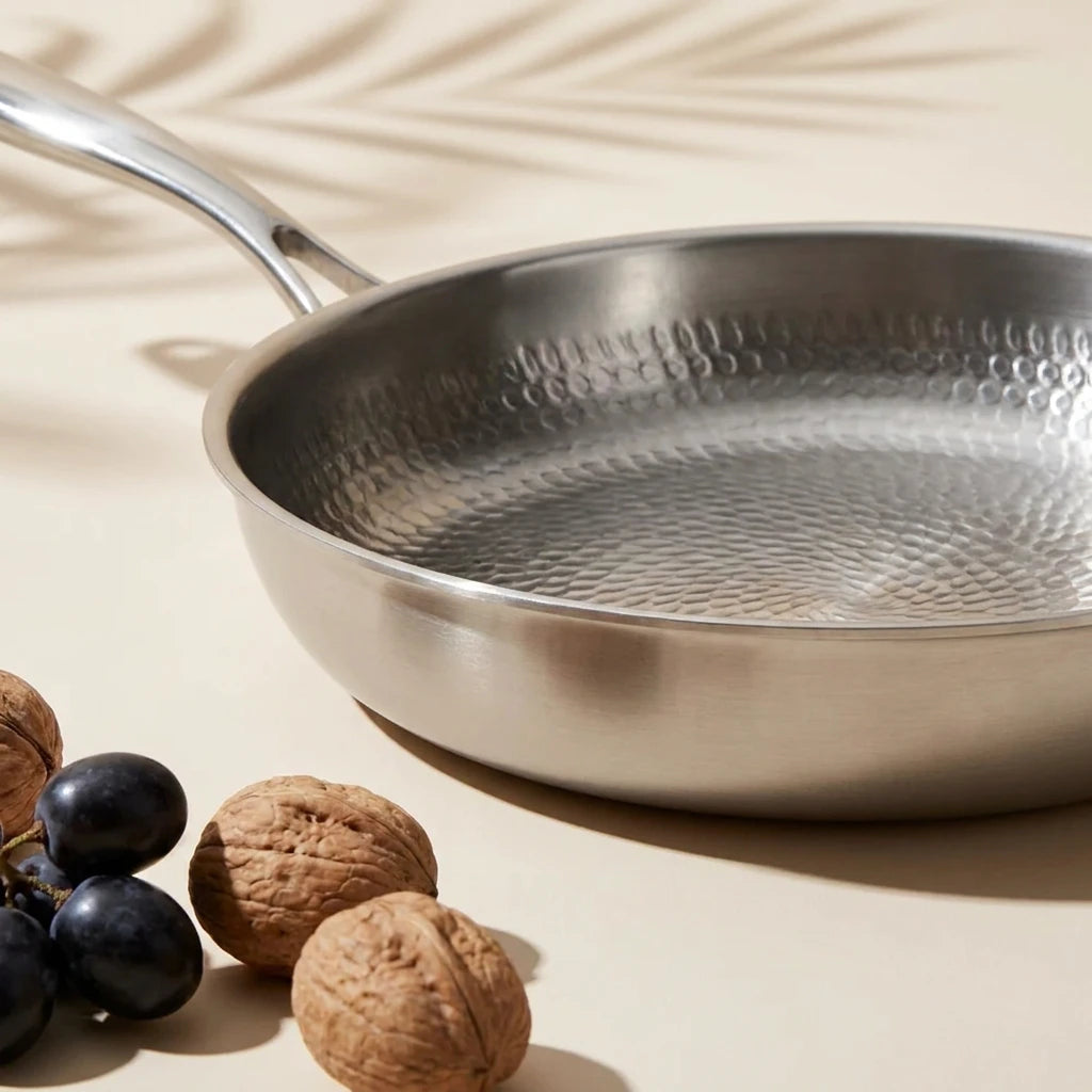 Poêle en titane 26 cm de trois quarts, sa surface martelée à côté de noix et de raisins noirs