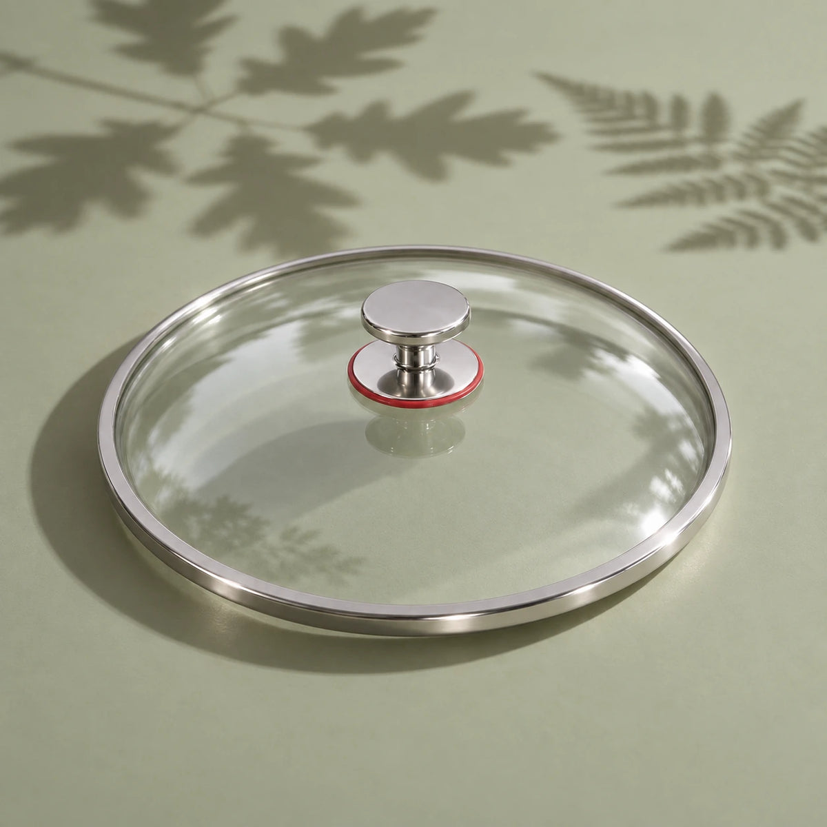 Le couvercle en verre de la poêle en titane 26 cm vu seul, avec son cerclage métallique et son bouton à bague rouge