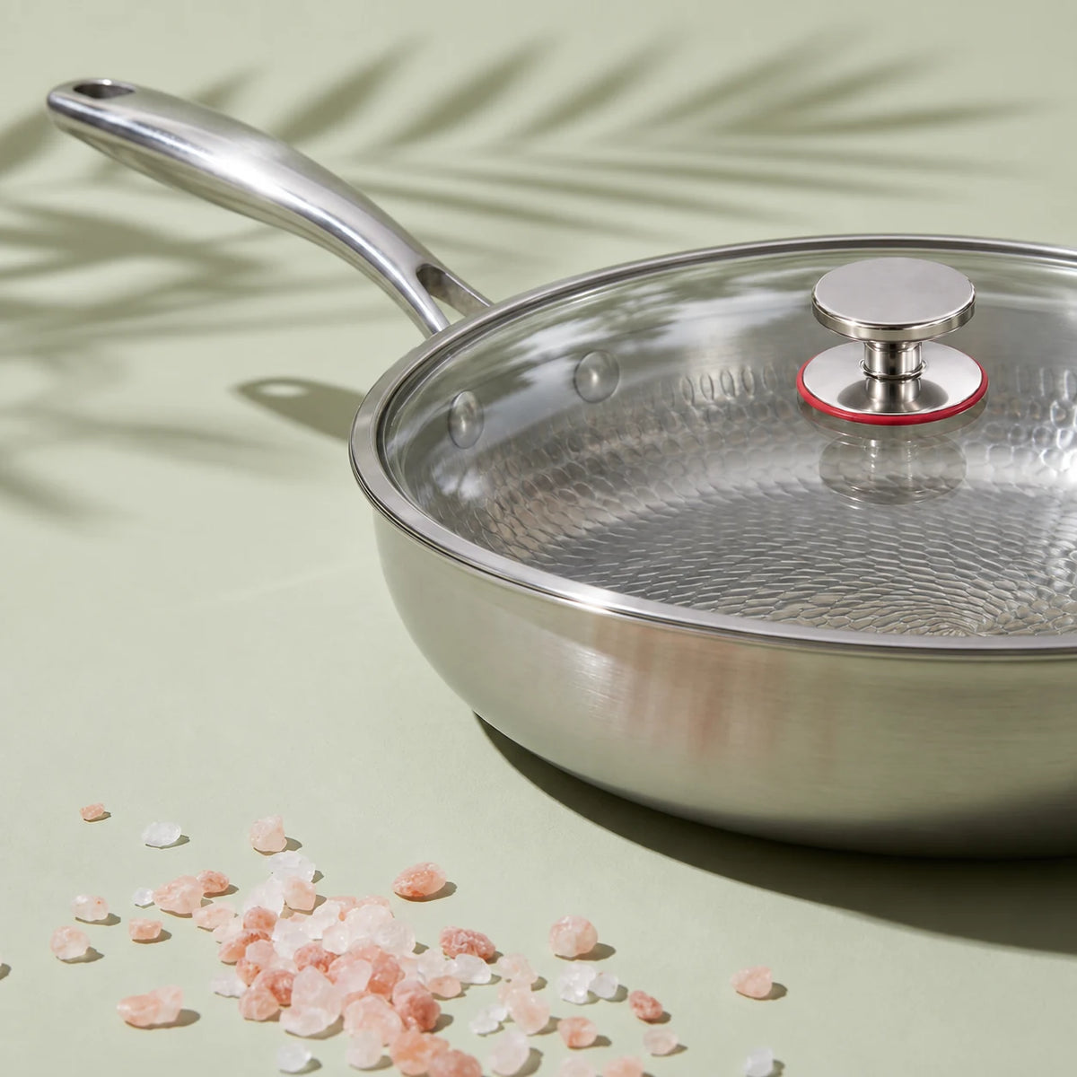 Poêle en titane avec couvercle 26 cm vue de près, couvercle en verre et bouton à bague rouge, cristaux de sel rose devant