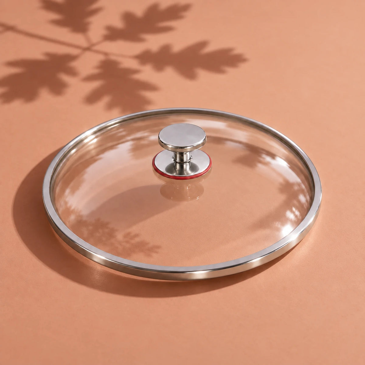 Le couvercle en verre de la poêle en titane 28 cm vu seul, avec son cerclage métallique et son bouton à bague rouge