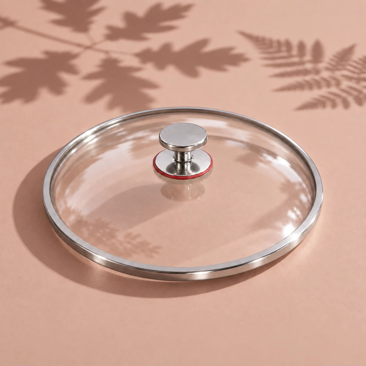 Le couvercle en verre de la poêle en titane 30 cm vu seul, avec son cerclage métallique et son bouton à bague rouge