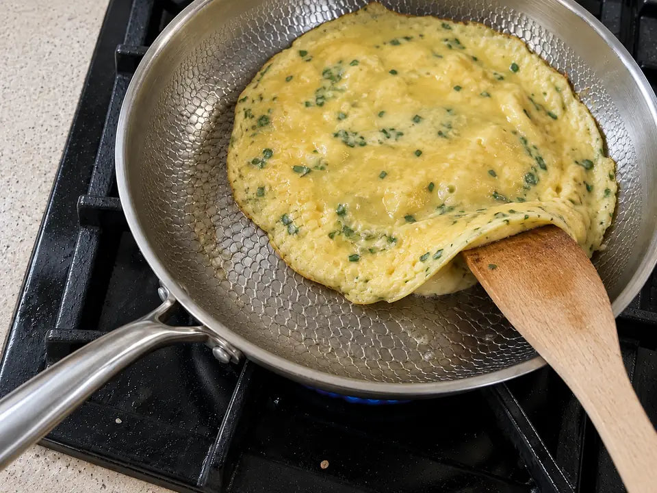 Avis sur la poêle en titane : une omelette aux herbes se décolle du bord d'un coup de spatule en bois, sans accrocher