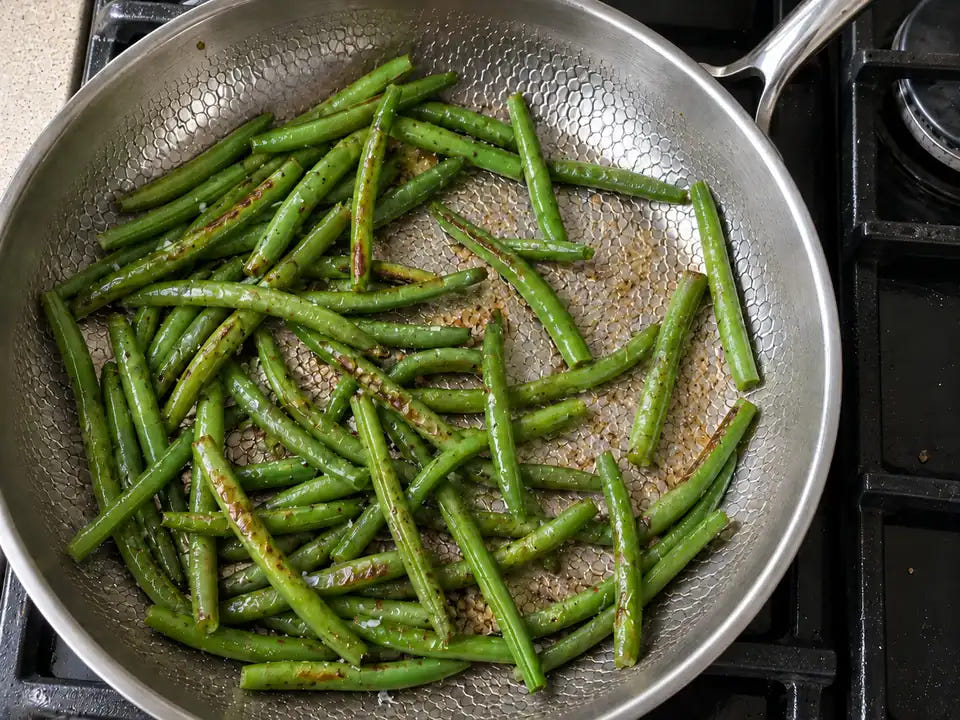Poêle en titane pur : des haricots verts cuisent directement sur la surface de cuisson martelée, sans aucun revêtement