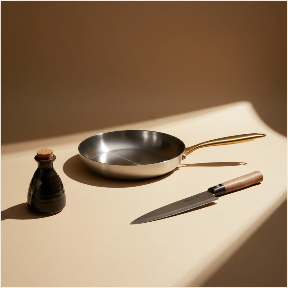 Poêle induction 26 cm vue de dessus, un flacon de sauce soja et un couteau posés à côté