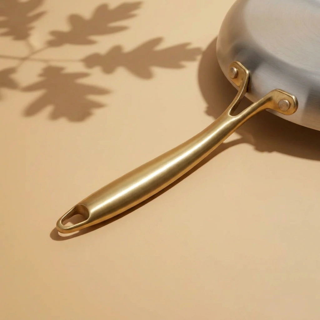 Manche doré de la poêle induction 30 cm vu de dessous, sa nervure centrale et sa fixation