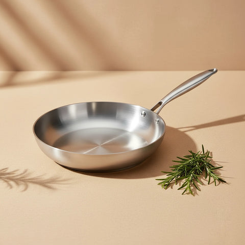 Poêle inox 18/10 28 cm : vue en perspective avec une branche de romarin.