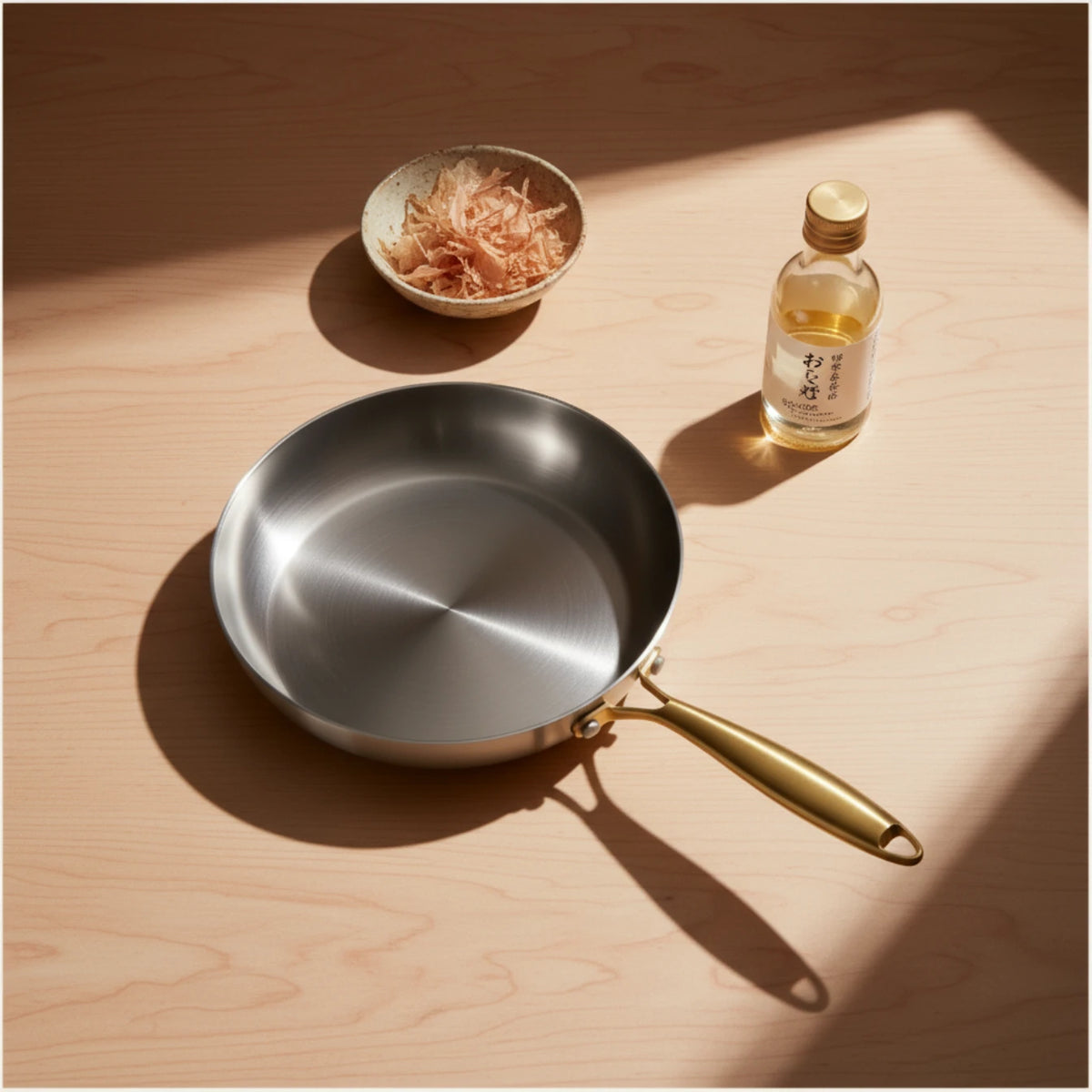Poêle inox 22 cm : présentation avec une bouteille de sauce et une coupelle.