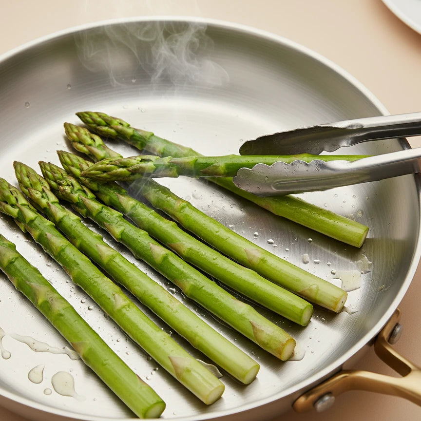 Poêle inox 26 cm : cuisson d’asperges vertes avec une pince.