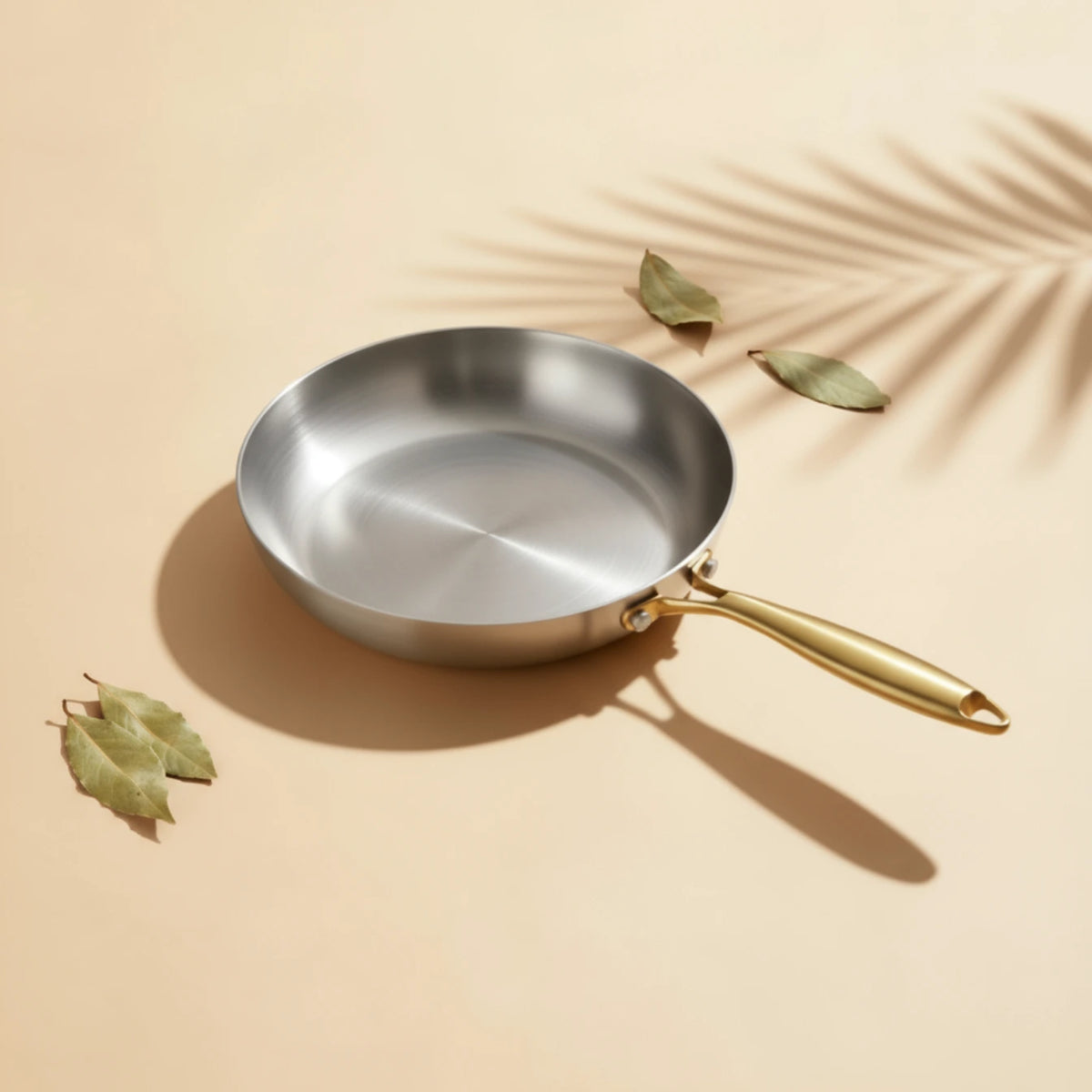 Poêle inox 30 cm : vue en perspective avec des feuilles de laurier.