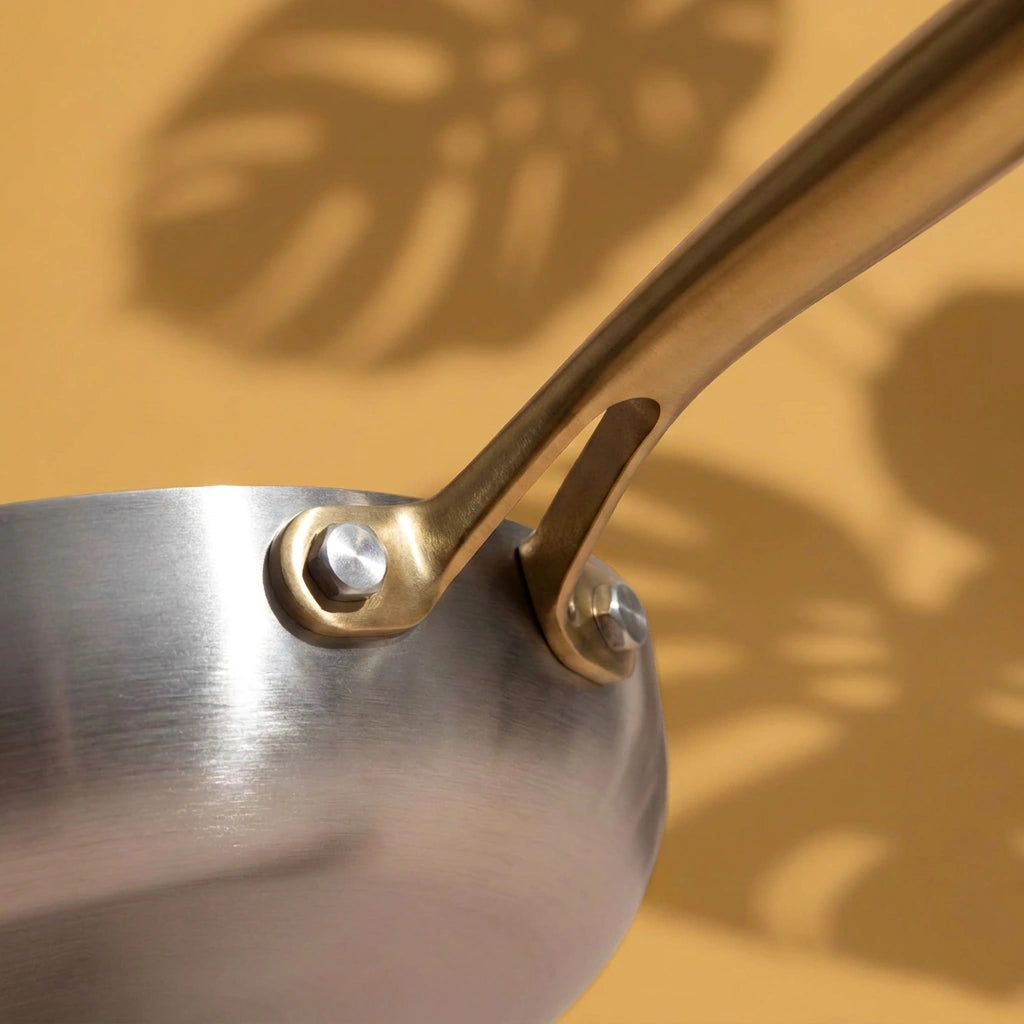 Fixation en fourche du manche doré de la poêle tous feux 24 cm, vue de dessous avec ses deux rivets
