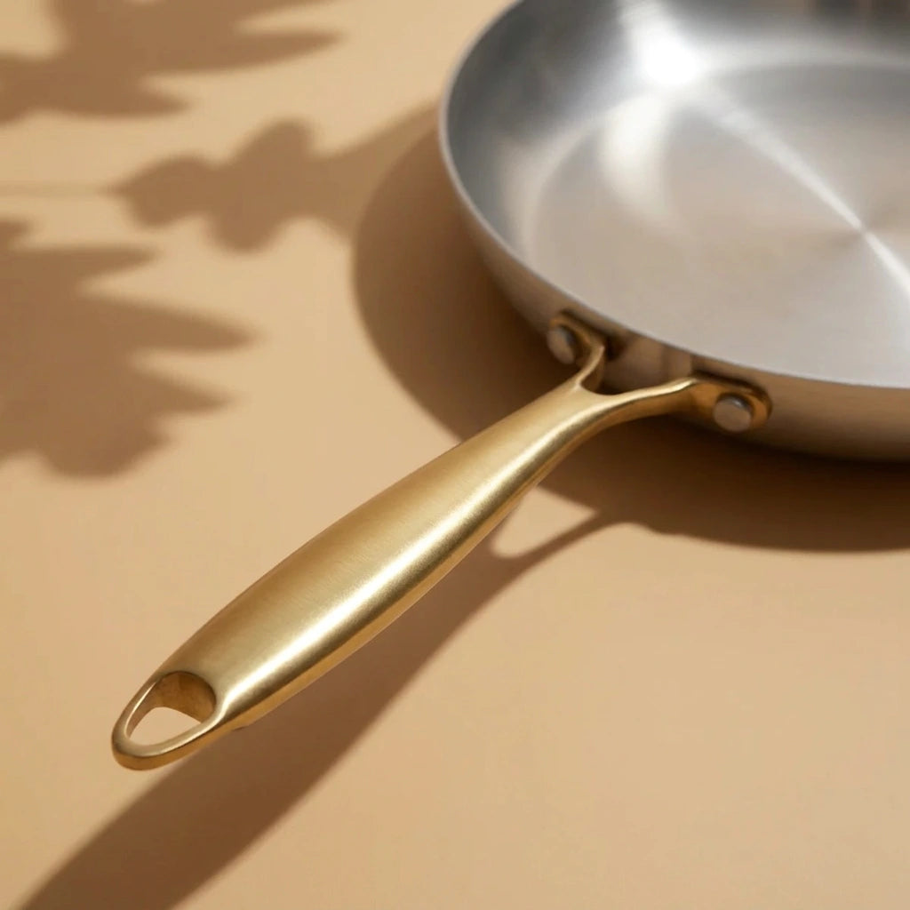 Manche doré de la poêle vitrocéramique 28 cm vu de dessus, avec la surface de cuisson en arrière-plan