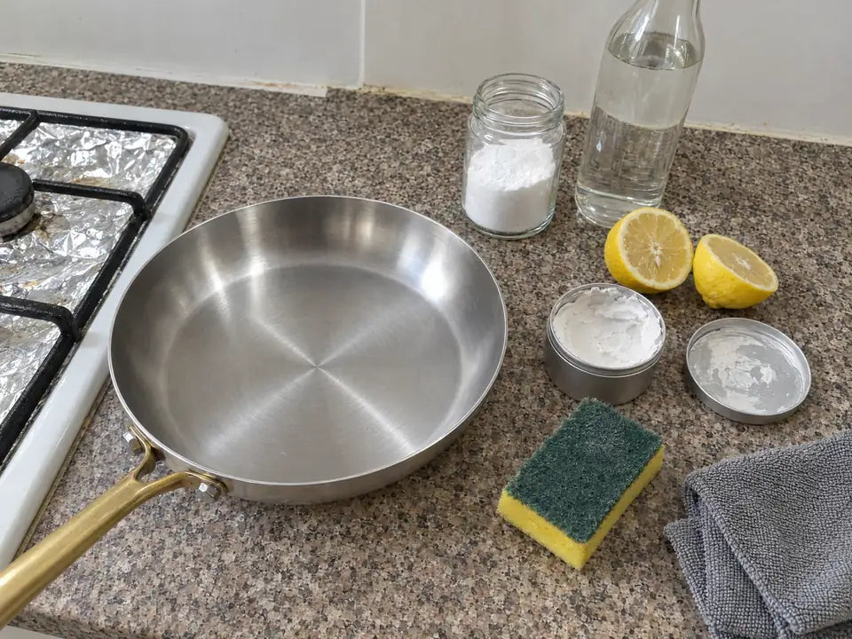 Produits pour nettoyer une poêle en inox : bicarbonate de soude, vinaigre blanc, citron, pierre d'argile et éponge