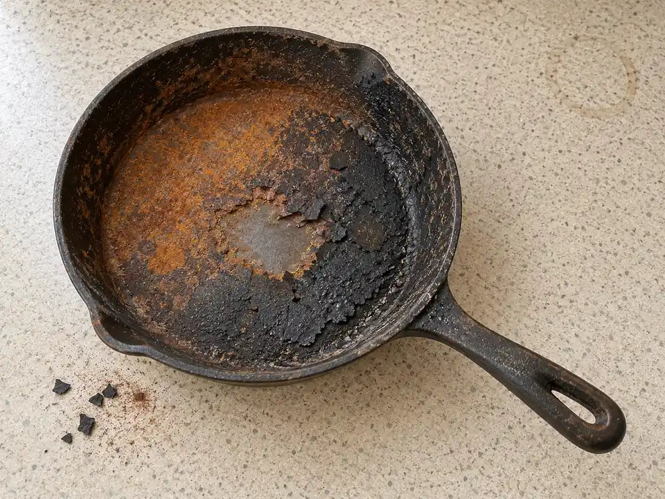 Poêle en fonte avant sa remise à neuf : de la rouille orange et une croûte noire écaillée recouvrent toute la poêle