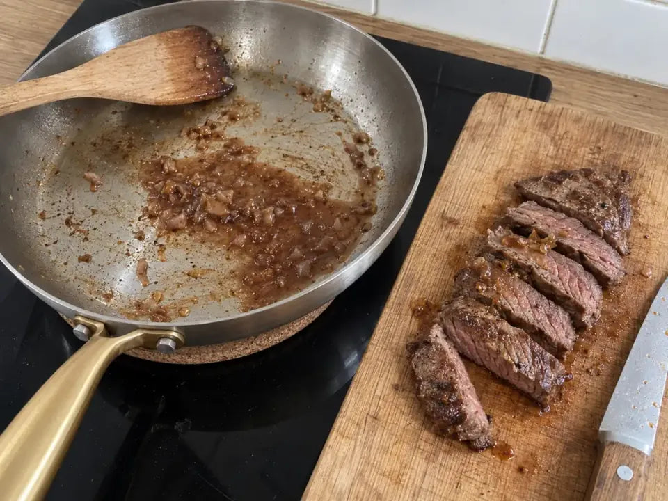Sauce aux échalotes préparée avec les sucs d'une poêle en inox, à côté d'une bavette tranchée et rosée à cœur