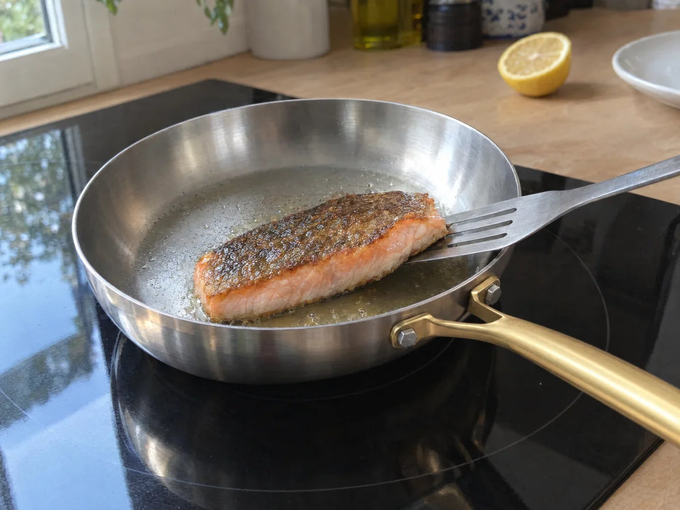 Filet de saumon à la peau dorée et croustillante qui se détache d'une poêle inox posée sur une plaque à induction